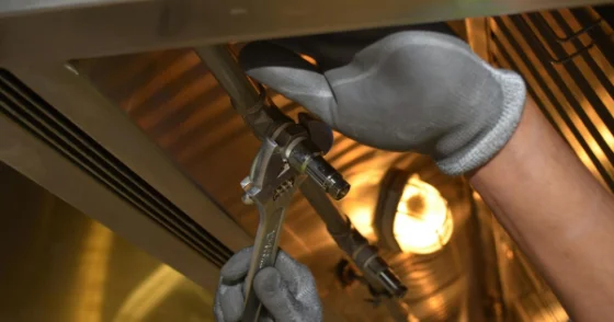 Tradesperson tightening a fitting with a wrench